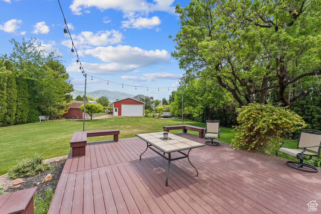 Wooden terrace with a mountain view, a yard, an outdoor structure, and a detached garage