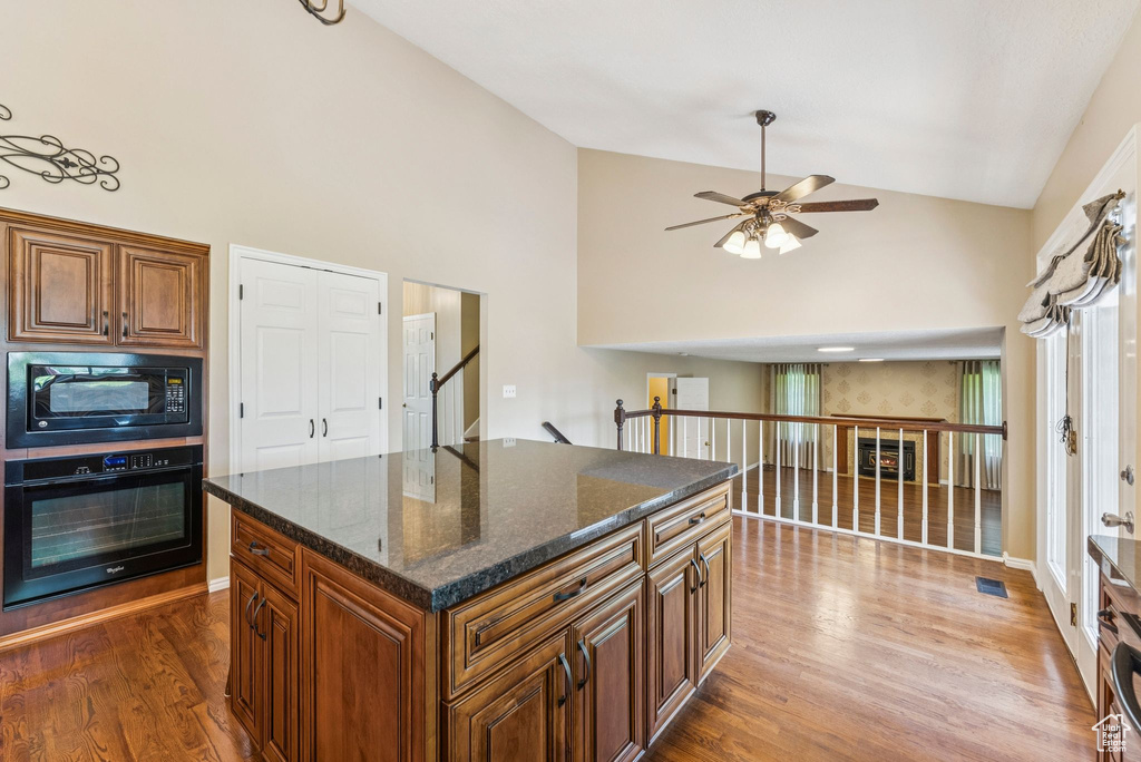 Kitchen featuring black appliances, dark wood-style flooring, ceiling fan, high vaulted ceiling, and brown cabinets