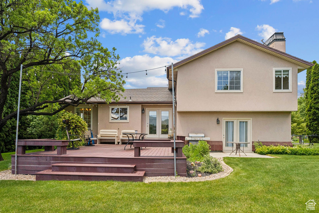 Back of property featuring french doors, a deck, a chimney, and stucco siding