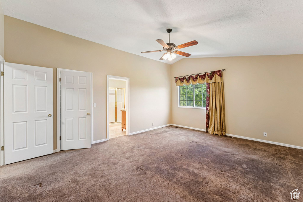 Unfurnished bedroom with vaulted ceiling, carpet floors, ceiling fan, and ensuite bath