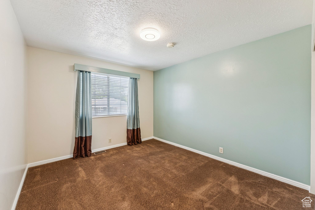 Spare room featuring carpet floors, a smoke detector, and a textured ceiling