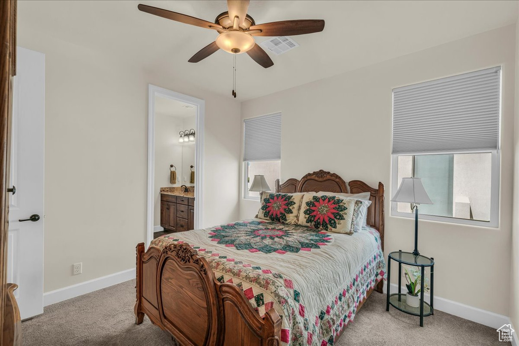 Carpeted bedroom featuring ensuite bath and a ceiling fan