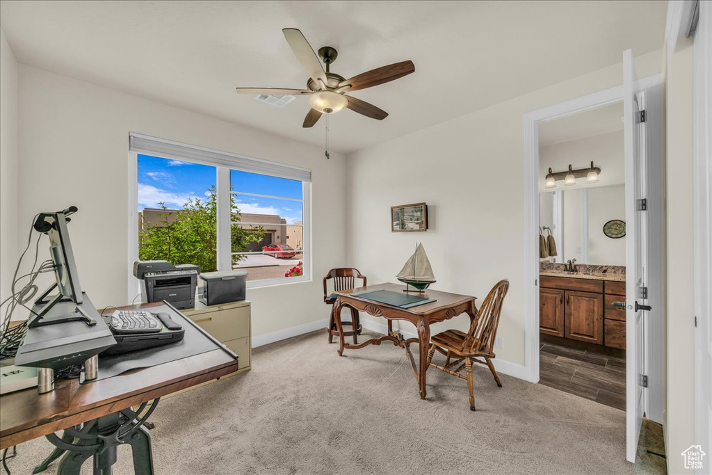 Home office featuring light carpet and a ceiling fan