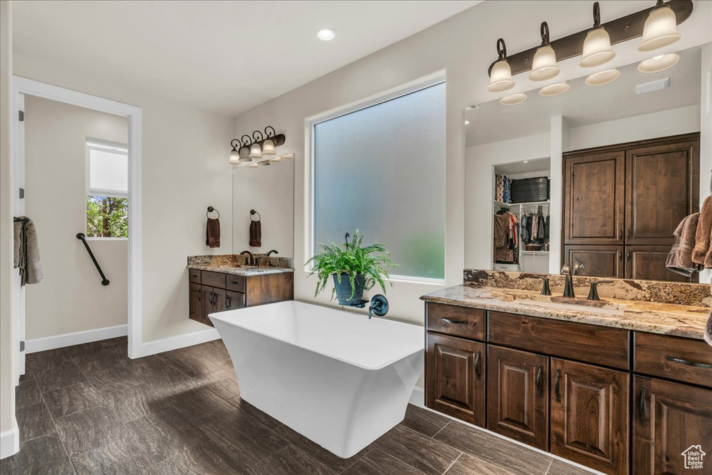Full bath featuring a freestanding tub, vanity, and a walk in closet