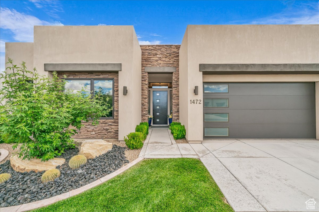 View of front of house featuring stone siding, driveway, and stucco siding