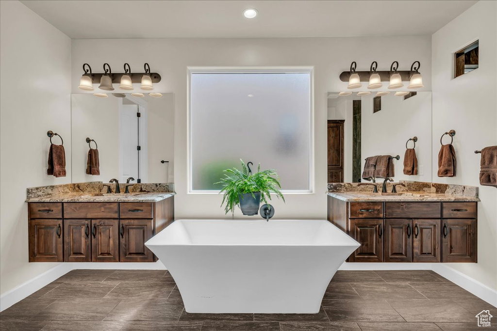 Bathroom featuring a freestanding bath, two vanities, and recessed lighting