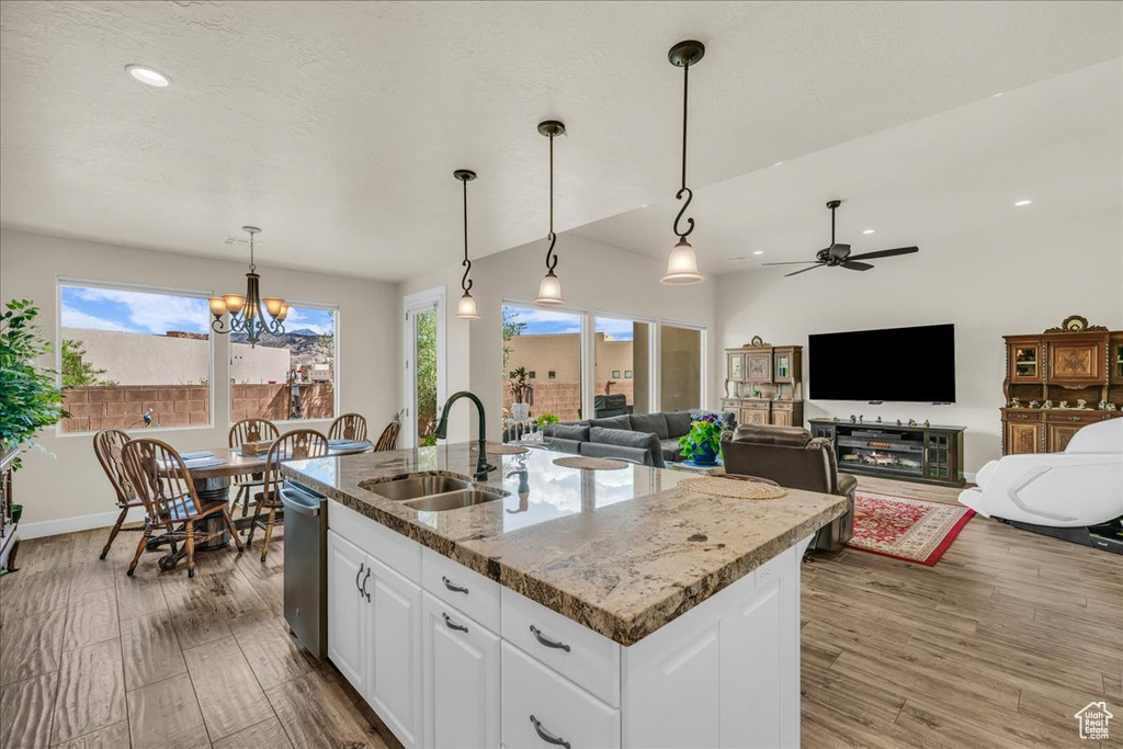 Kitchen featuring healthy amount of natural light, a kitchen island with sink, wood finished floors, white cabinets, and recessed lighting