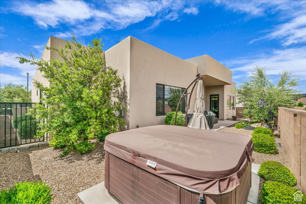 Rear view of house featuring a hot tub and stucco siding