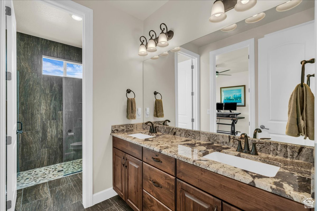 Bathroom featuring a shower stall, double vanity, and ceiling fan
