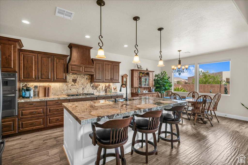 Kitchen with premium range hood, stainless steel appliances, decorative backsplash, recessed lighting, and wood finished floors