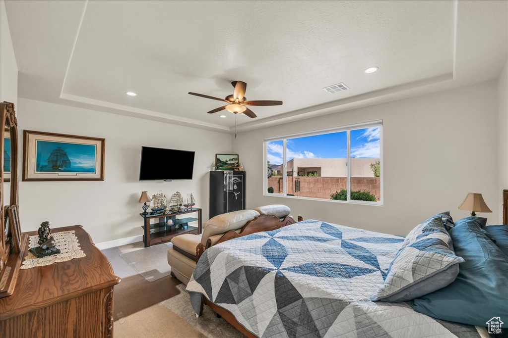 Bedroom featuring a tray ceiling, recessed lighting, a ceiling fan, and wood finished floors