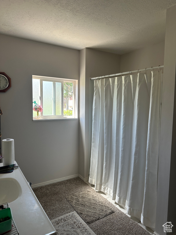 Bathroom with a textured ceiling, vanity, and curtained shower