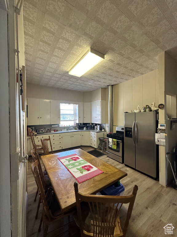 Kitchen featuring stainless steel appliances, an ornate ceiling, and light wood-style flooring