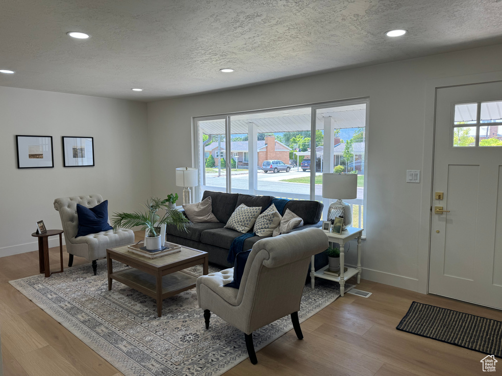 Living area with a textured ceiling, recessed lighting, and light wood-style flooring