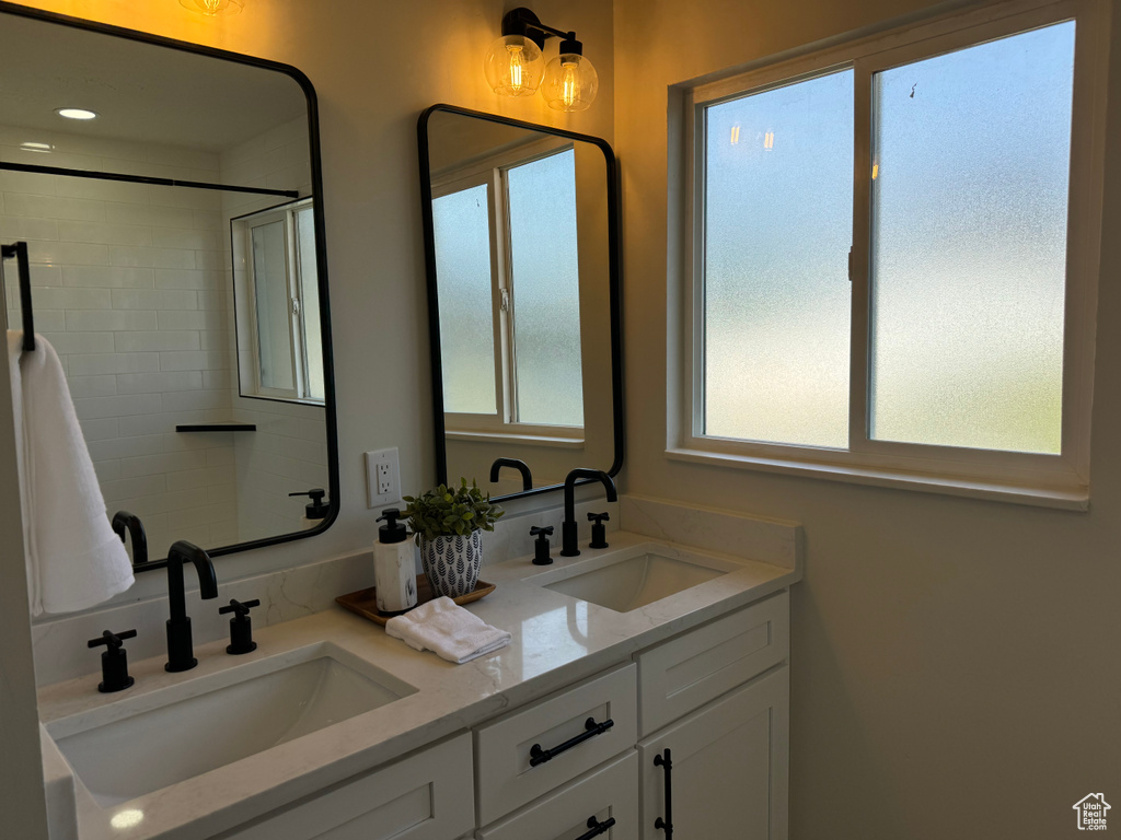 Full bath featuring double vanity and healthy amount of natural light