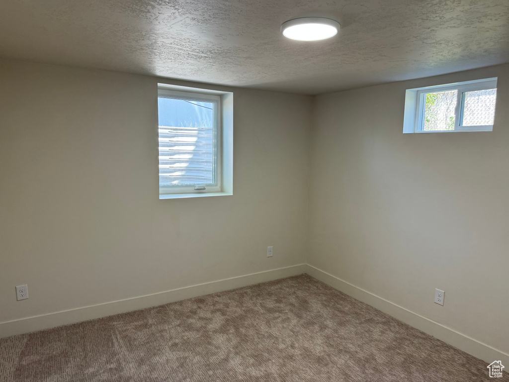 Carpeted spare room featuring baseboards and a textured ceiling