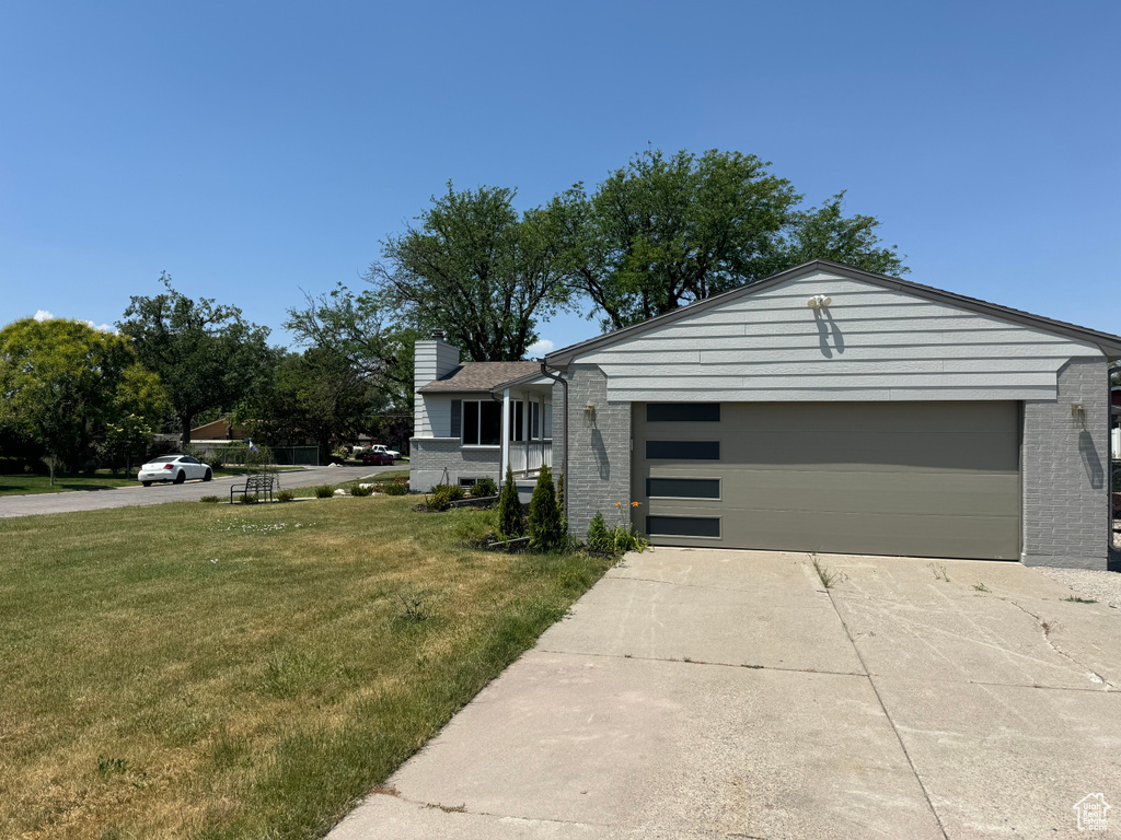 View of front facade with brick siding, a garage, a front yard, and concrete driveway