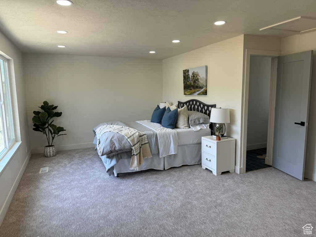 Carpeted bedroom with recessed lighting and multiple windows
