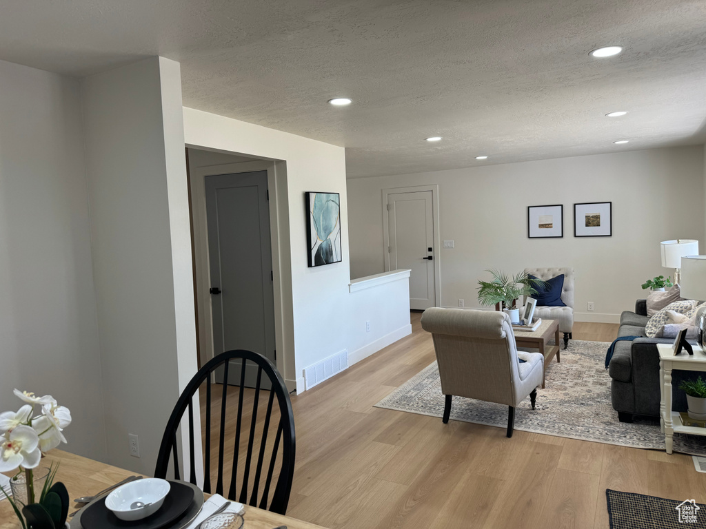 Living area with recessed lighting, light wood-type flooring, and a textured ceiling