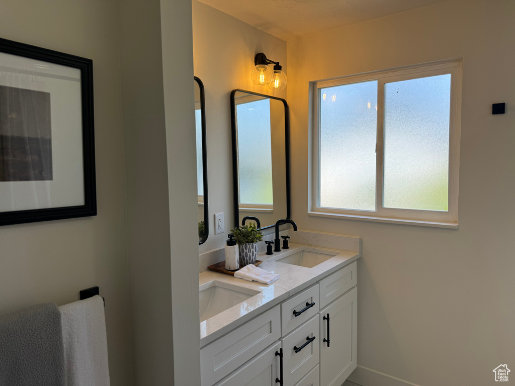 Full bathroom with double vanity and baseboards