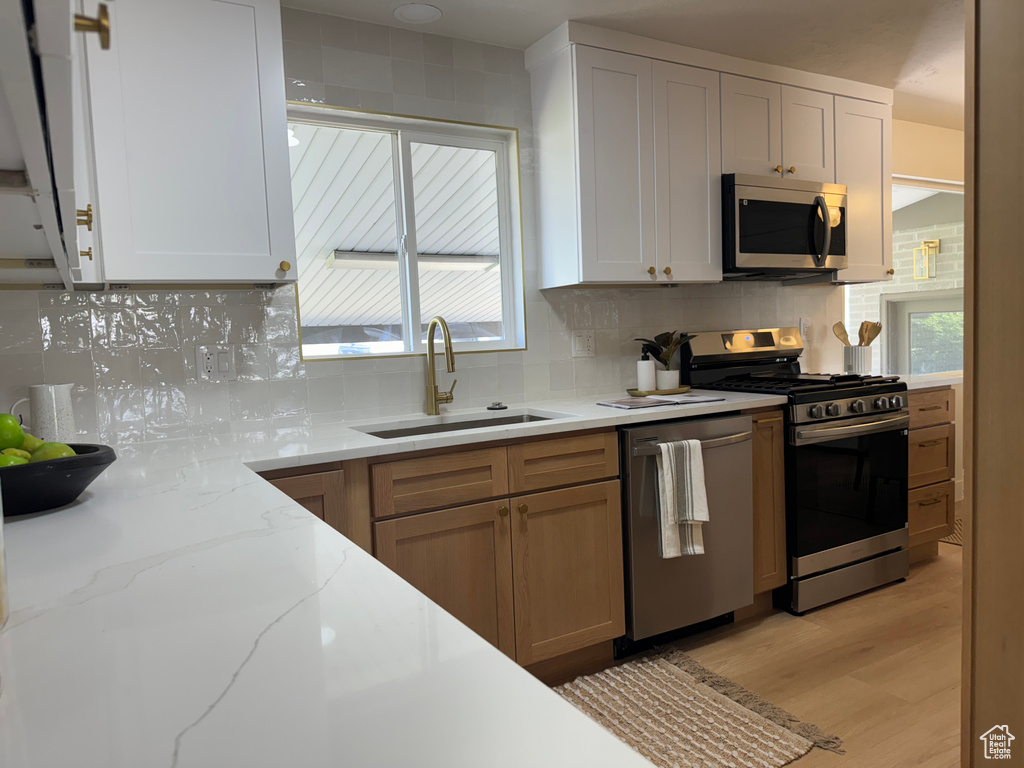 Kitchen featuring appliances with stainless steel finishes, decorative backsplash, and light stone counters