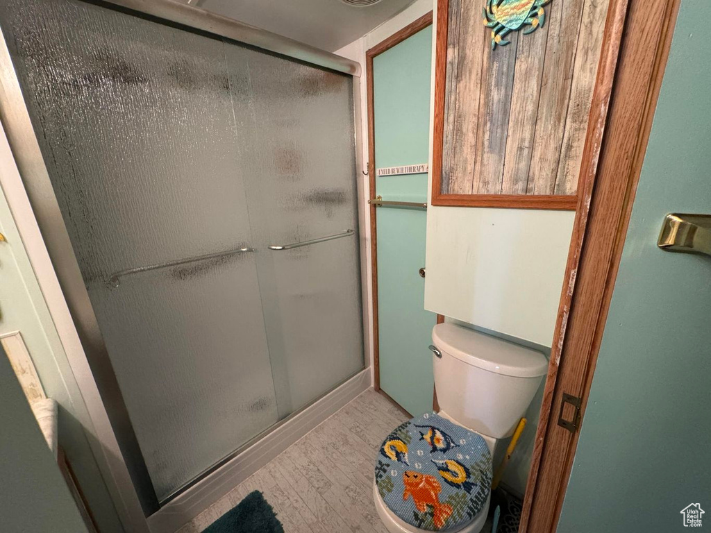 Full bath with wood finished floors and a stall shower