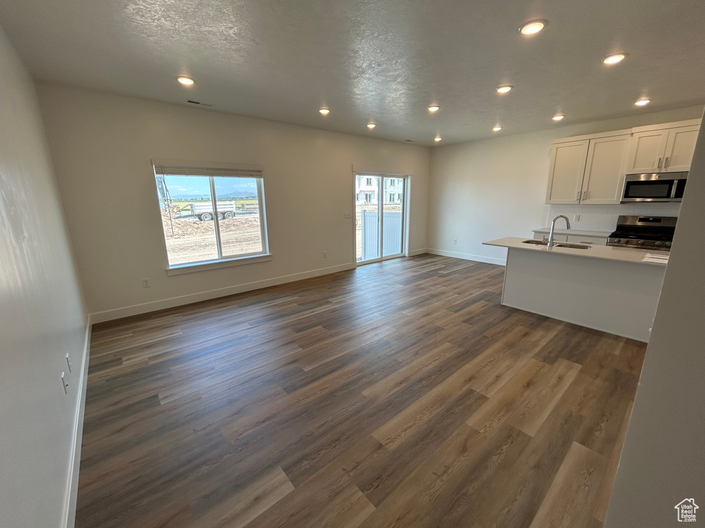 Kitchen featuring stainless steel appliances, open floor plan, recessed lighting, white cabinetry, and dark wood-style flooring