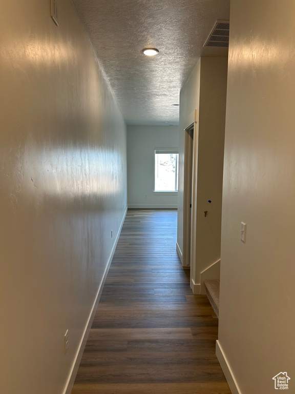 Hall featuring wood finished floors, a textured ceiling, and stairway