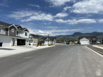 View of asphalt road featuring a residential view, a mountain view, and street lighting