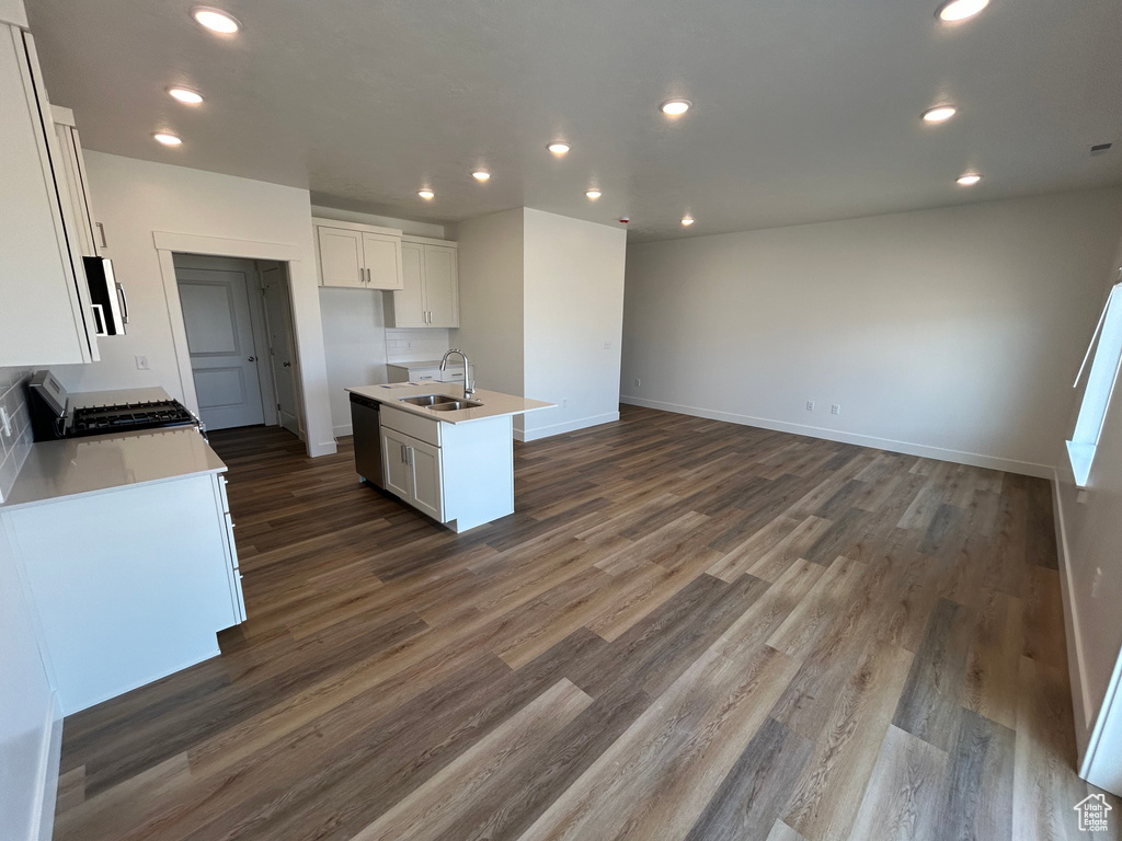Kitchen with stainless steel appliances, open floor plan, dark wood-style flooring, white cabinets, and recessed lighting