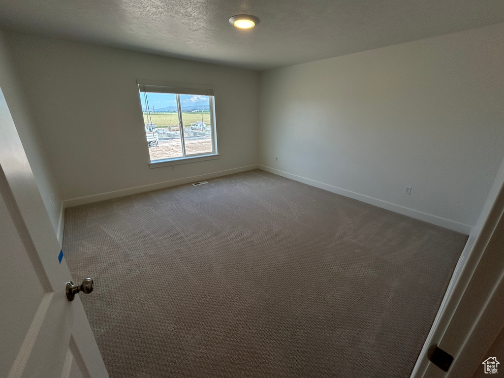 Carpeted spare room featuring baseboards
