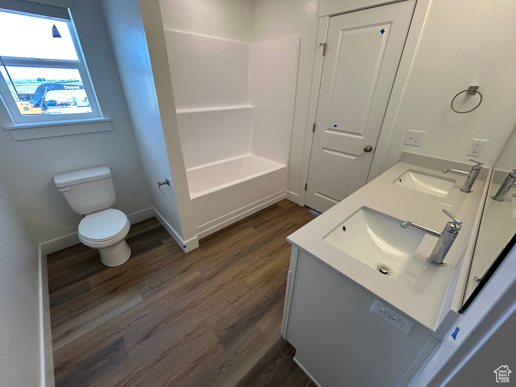 Bathroom with wood finished floors, double vanity, and bathing tub / shower combination