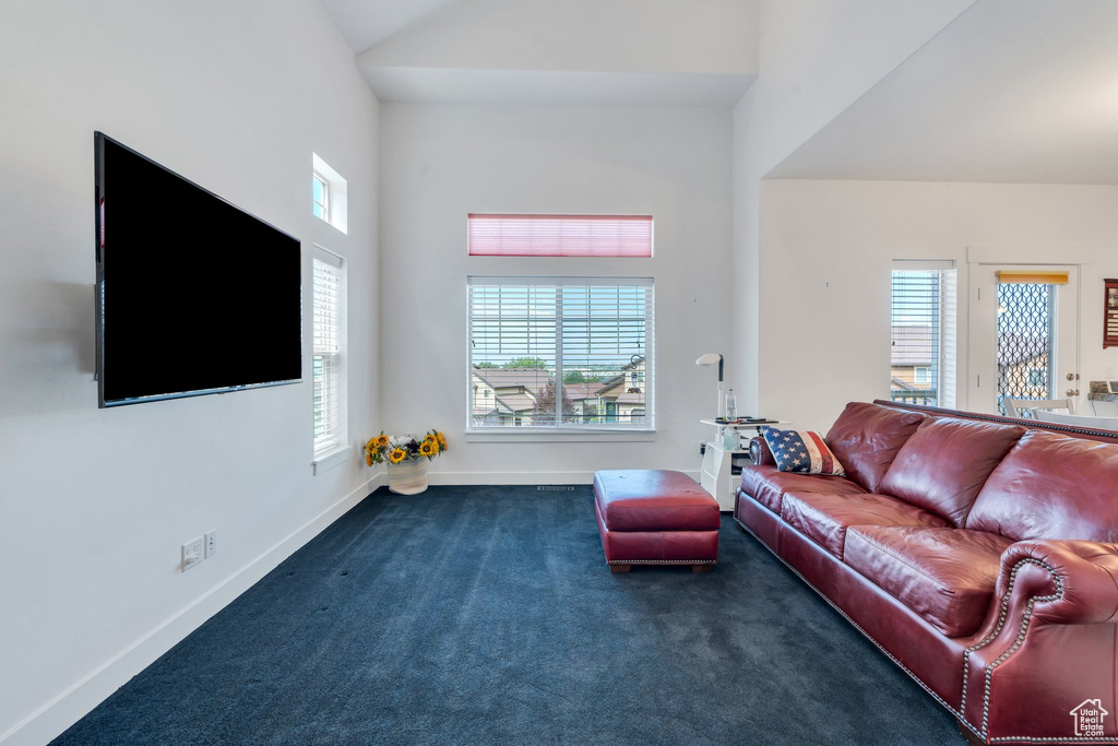 Carpeted living room featuring baseboards and high vaulted ceiling