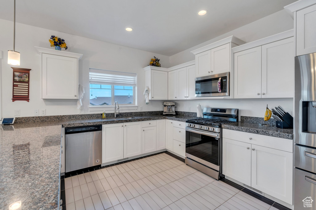 Kitchen featuring appliances with stainless steel finishes, white cabinetry, recessed lighting, decorative light fixtures, and light tile patterned flooring