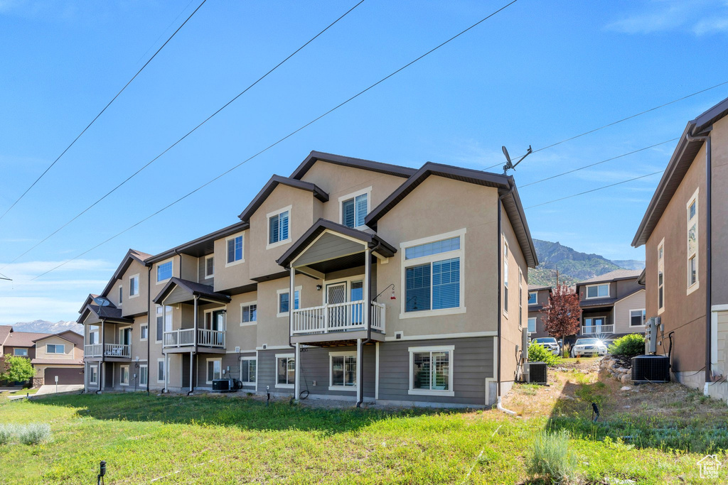 Rear view of house with stucco siding, a yard, a balcony, a residential view, and a mountain view