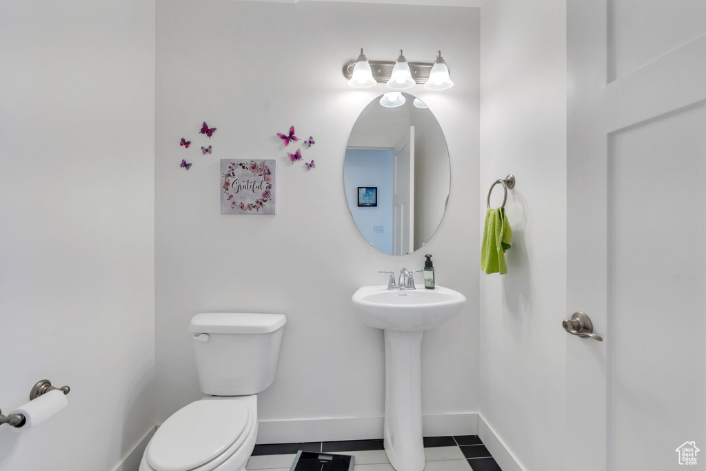 Half bathroom with toilet and tile patterned flooring