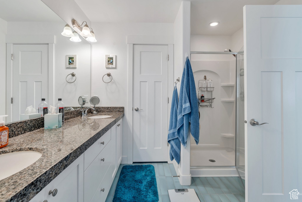 Bathroom with a shower stall, double vanity, and tile patterned flooring