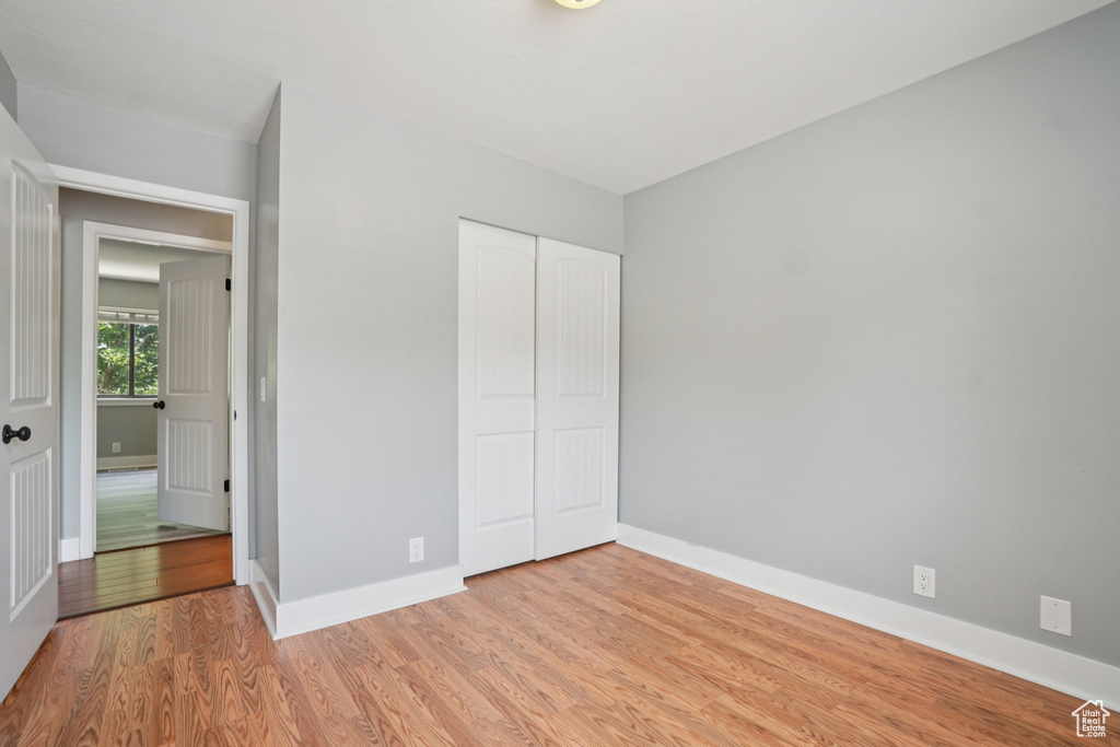 Unfurnished bedroom with light wood-style floors and a closet