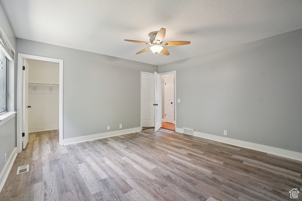 Unfurnished bedroom with wood finished floors, ceiling fan, and a spacious closet