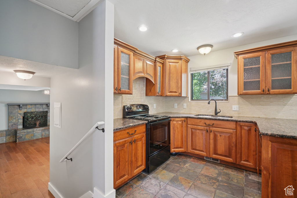 Kitchen featuring black range, dark stone countertops, decorative backsplash, glass insert cabinets, and recessed lighting