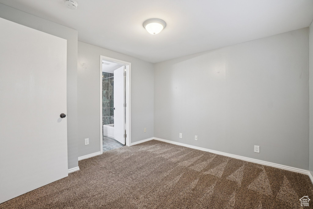 Carpeted empty room with a smoke detector and baseboards