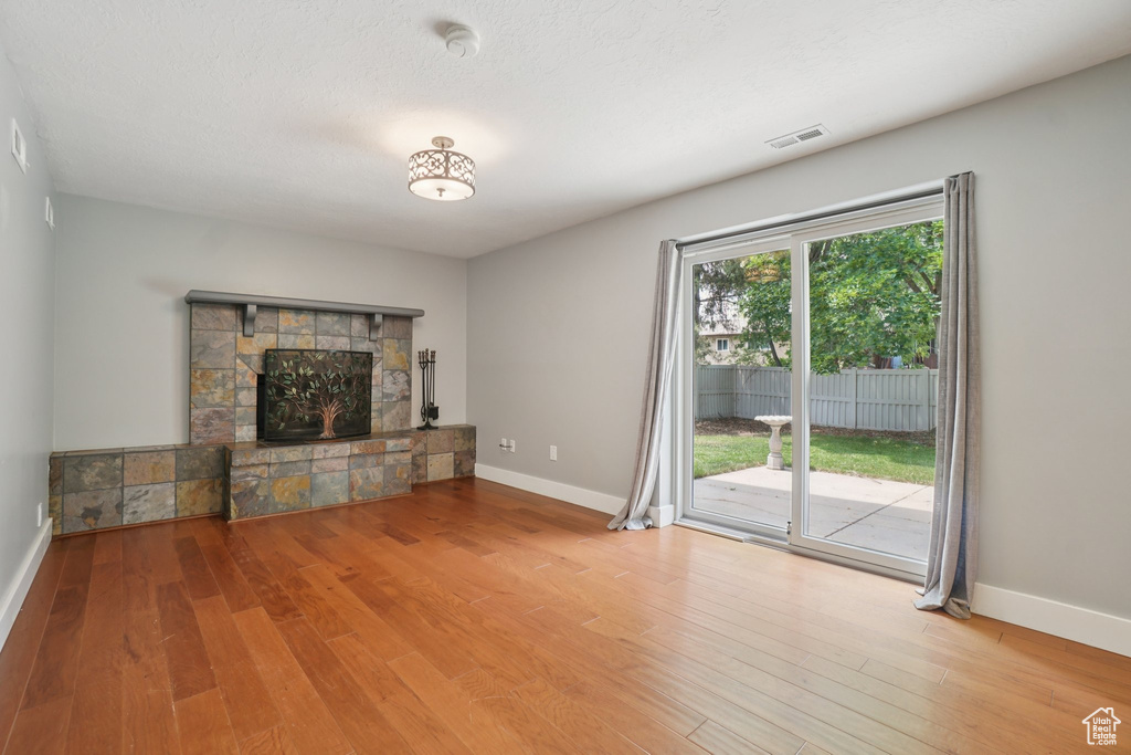Unfurnished living room with wood finished floors and a stone fireplace