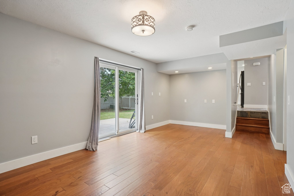 Spare room with a smoke detector, stairs, light wood-style flooring, and recessed lighting