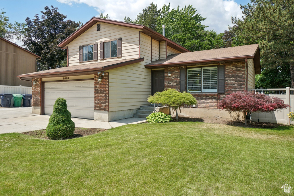 Split level home with brick siding, an attached garage, concrete driveway, and roof with shingles