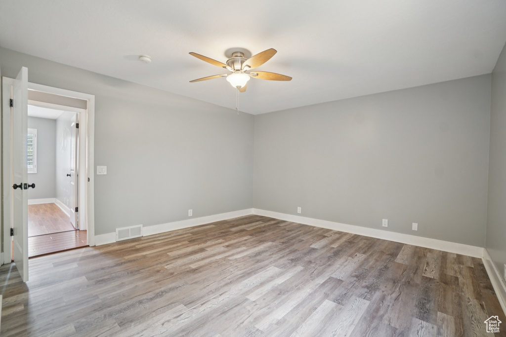 Unfurnished room featuring ceiling fan, wood finished floors, and a smoke detector