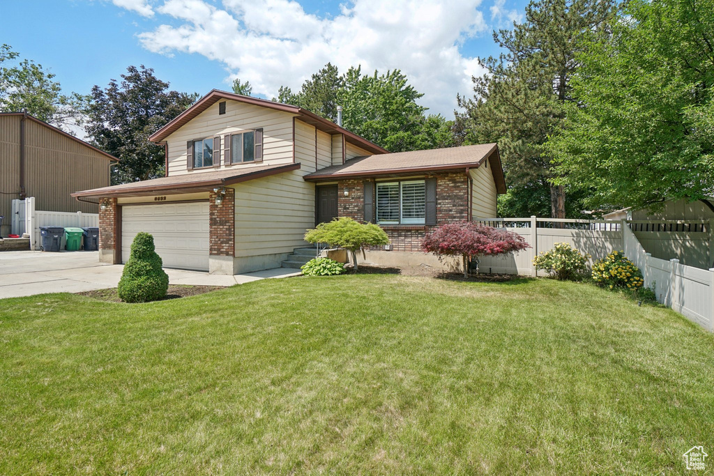Split level home with brick siding, a garage, and concrete driveway