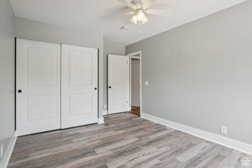 Unfurnished bedroom featuring wood finished floors, a closet, and ceiling fan