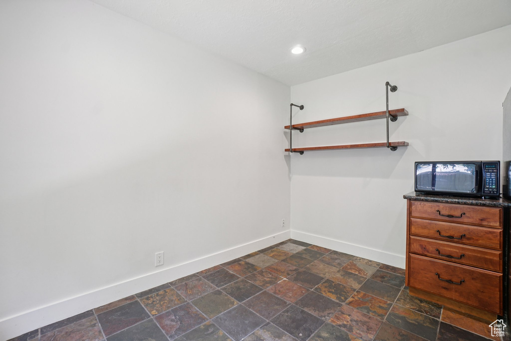 Unfurnished dining area with dark stone finish floors and recessed lighting