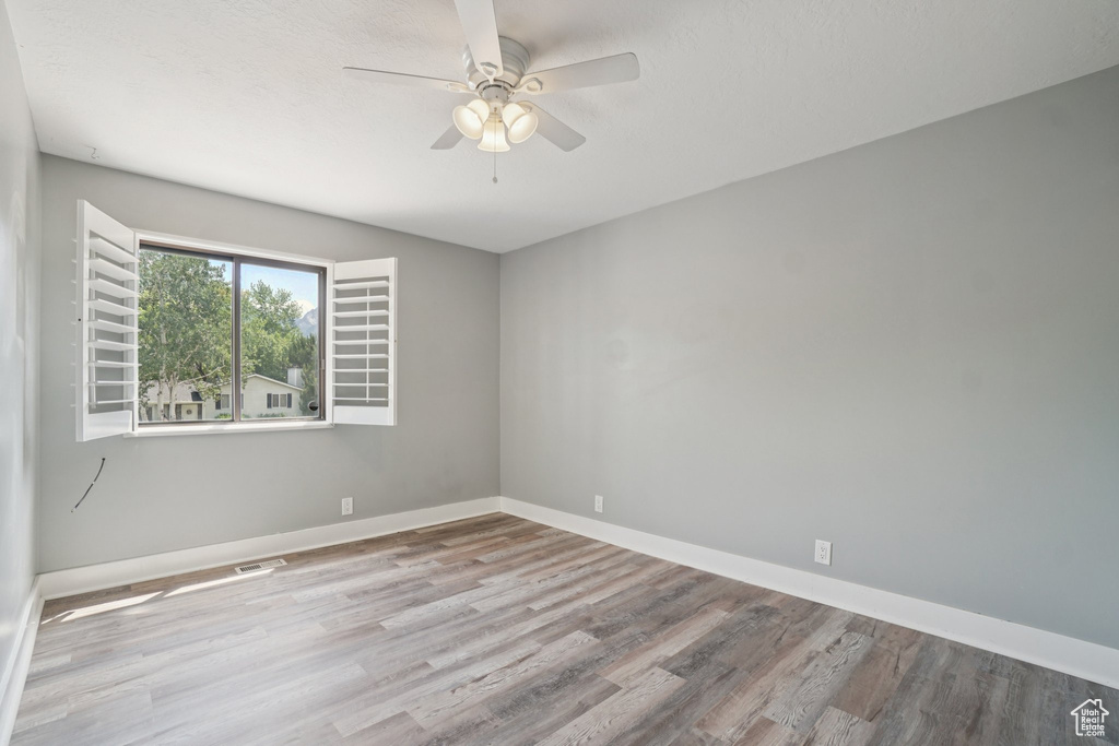 Spare room with wood finished floors and a ceiling fan