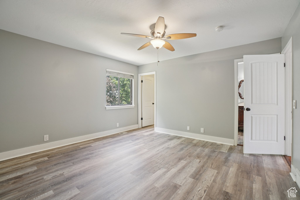 Unfurnished room with ceiling fan, wood finished floors, and a smoke detector